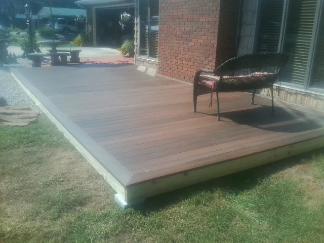 New wood deck and wicker chair beside a brick house in Lisbon